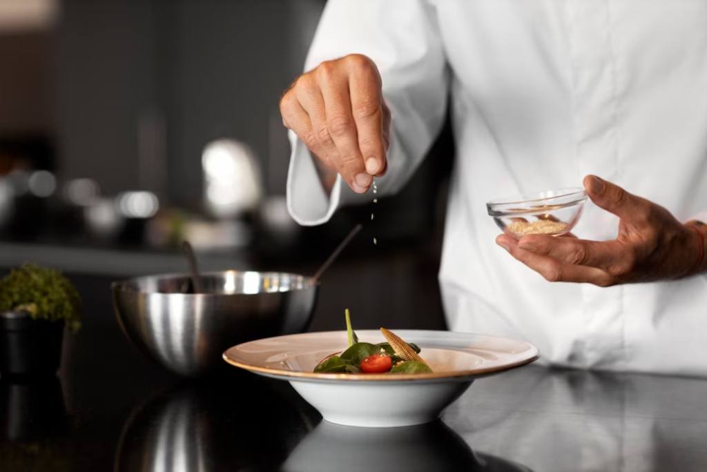 Chef delicately sprinkling seasoning on a gourmet dish in a kitchen